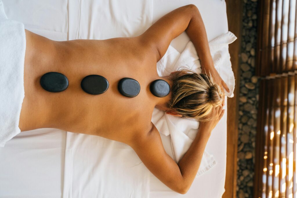 A serene hot stone massage therapy session with smooth black stones placed on the back for relaxation.